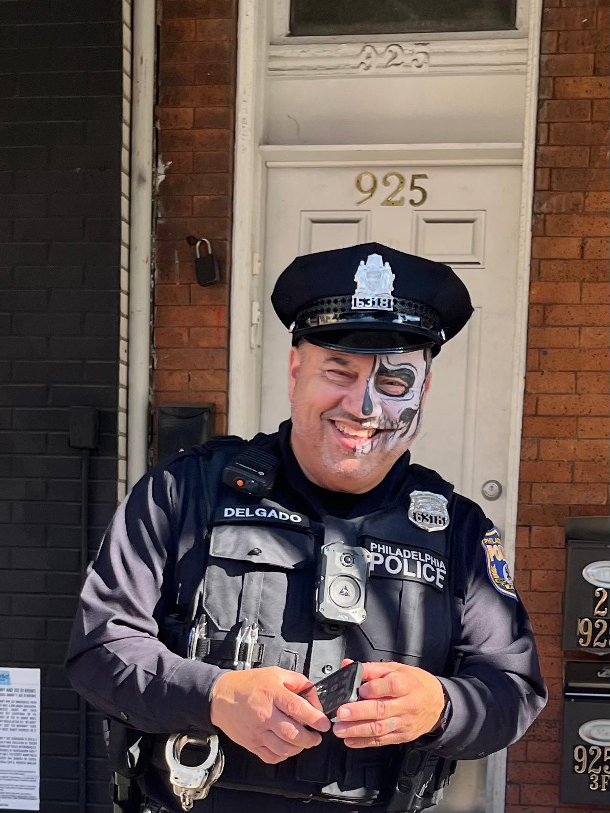 Smiling Philadelphia police officer wearing half-face sugar skull makeup